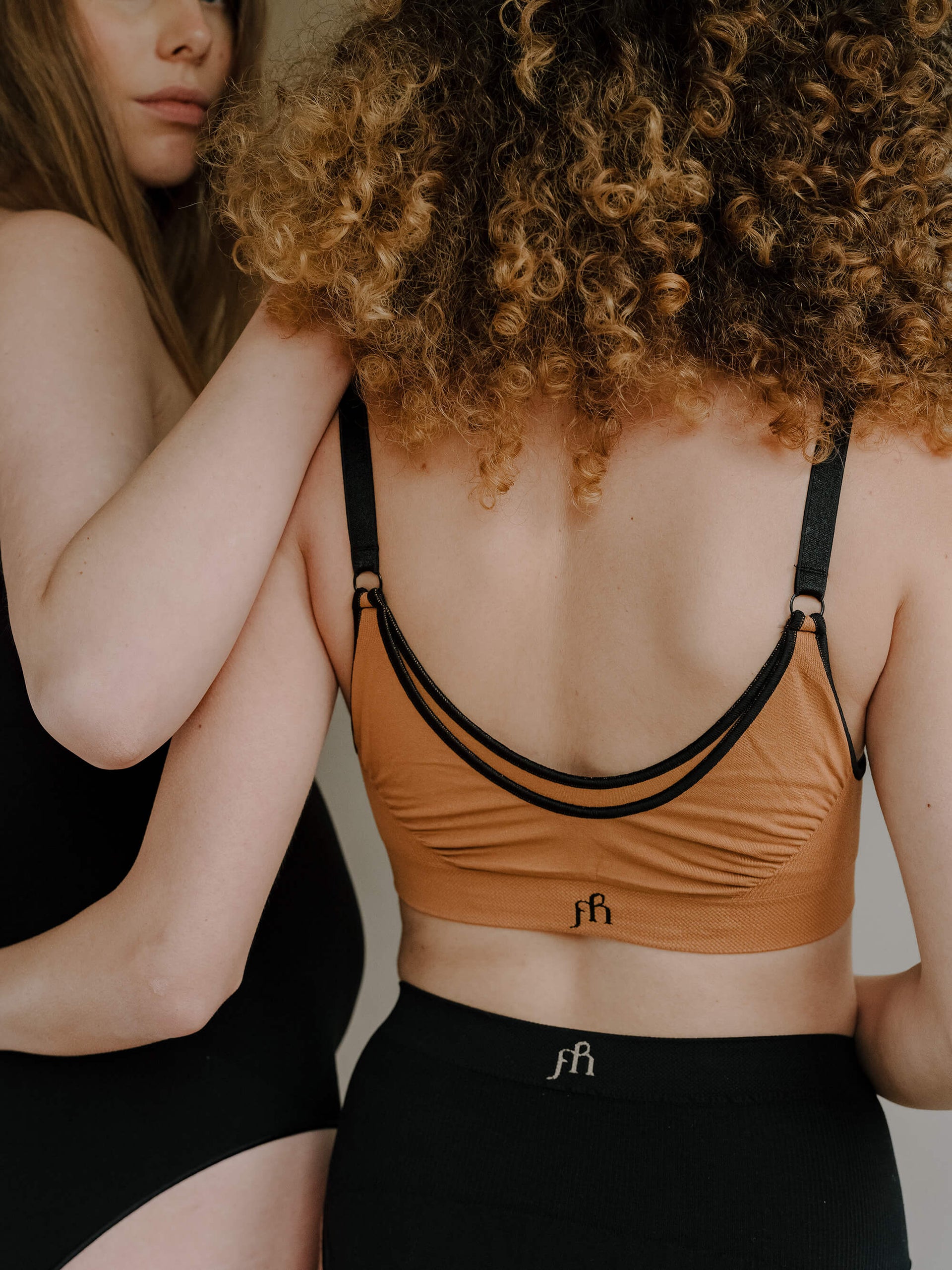 Jorgen House Image of two women, one wearing black maternity bodysuit and the other wearing hazel colour maternity bra and black briefs