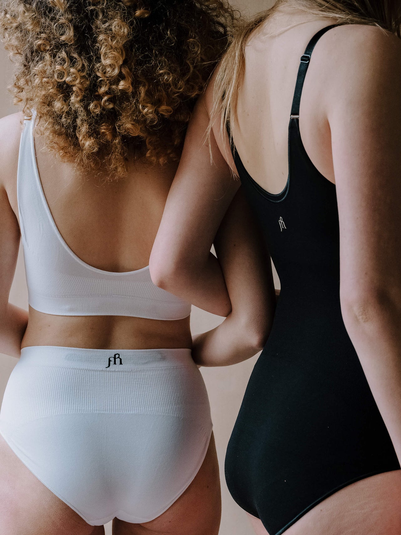 Jorgen House image of two women wearing white brief and bra and black bodysuit