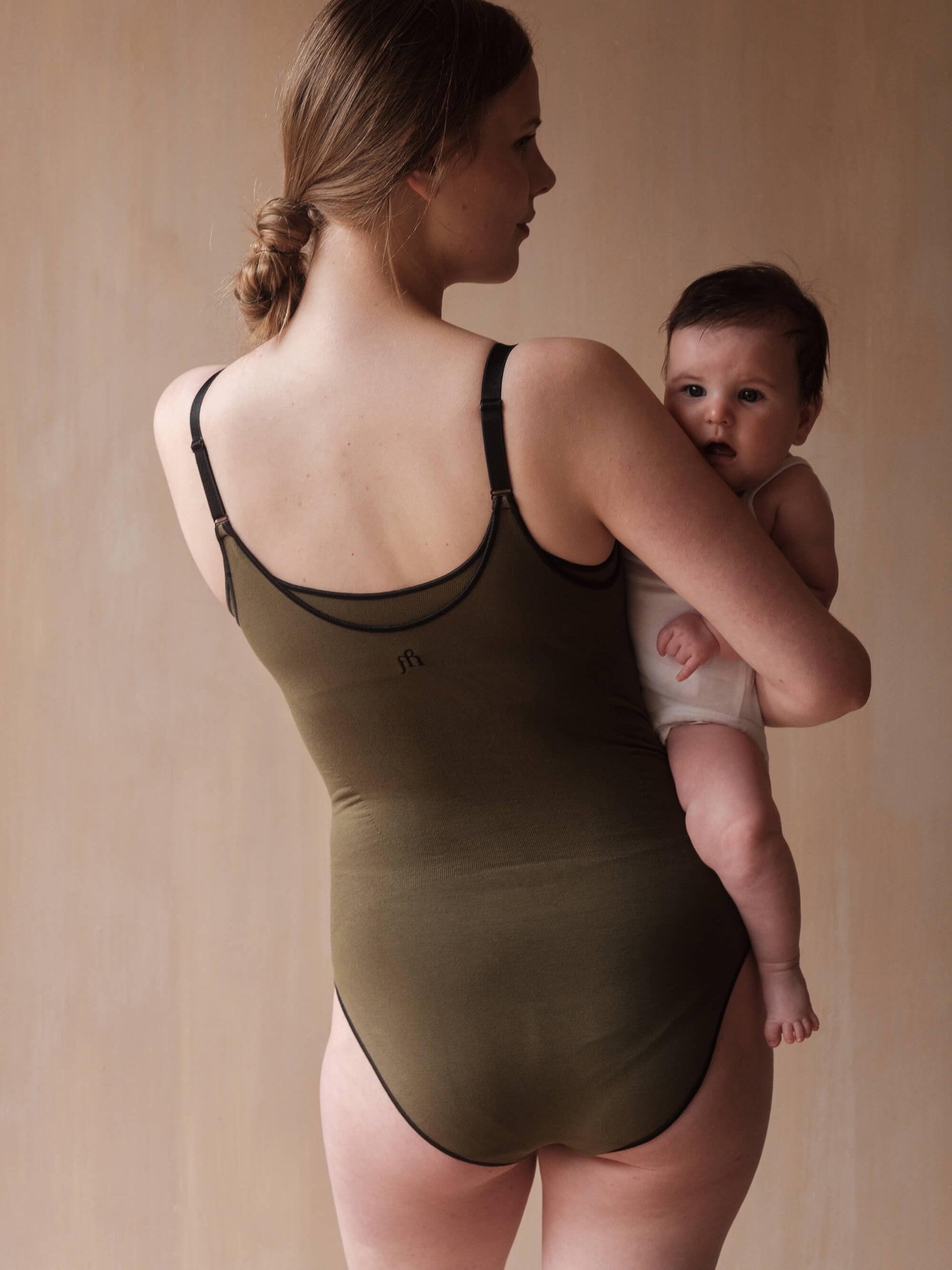 Jorgen House Dark olive green strap bodysuit on female body holding her baby