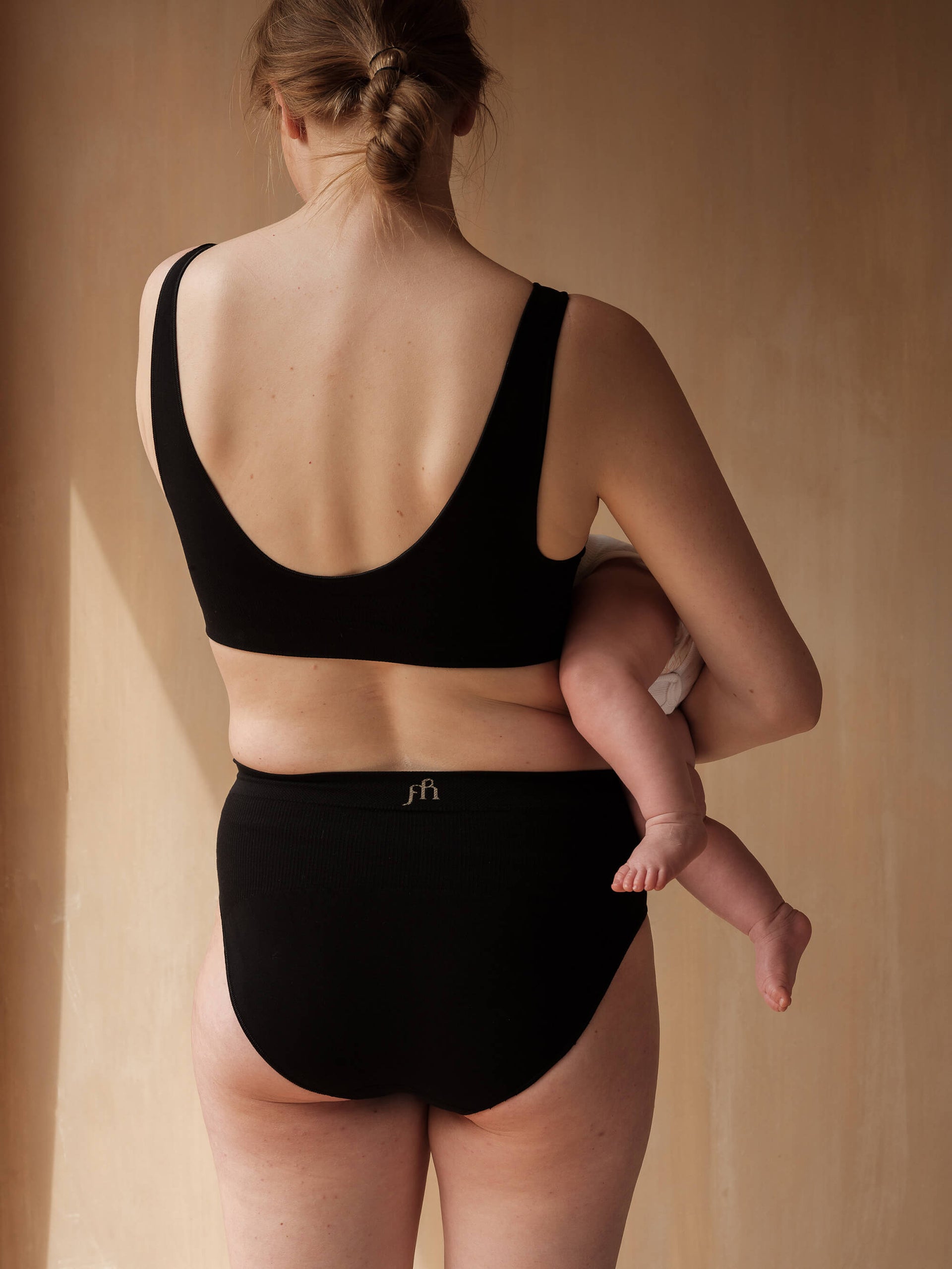 Jorgen House black colour maternity breastfeeding bra and briefs on a female body feeding her baby