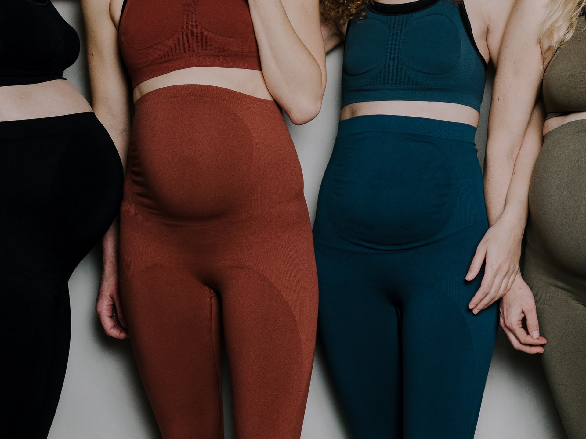 Jorgen House group shot of four women wearing the maternity sports leggings in black, brick red, midnight blue and dark olive green 